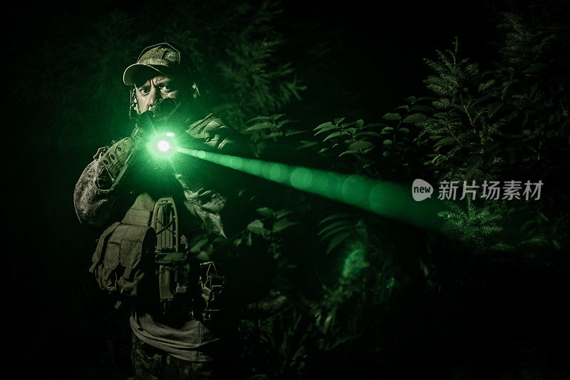 夜间军事特殊行动操作员在行动与绿色激光瞄准近摄像机