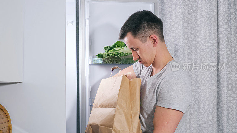一个年轻人把不同的食品放进大冰箱