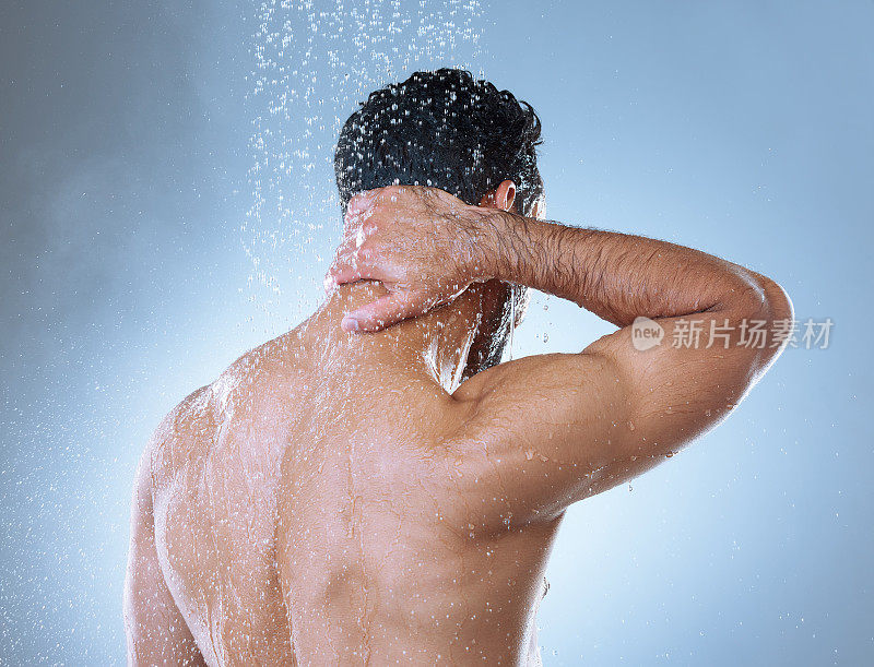后视镜摄影棚拍摄的一个不认识的年轻人在淋浴中洗头，背景是灰色的
