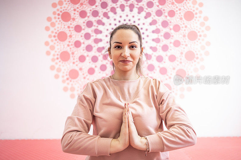 一位穿着粉红色运动服的年轻女子正在练习瑜伽