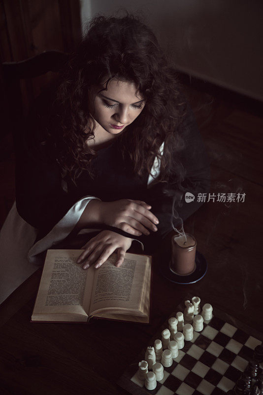 年轻女子的肖像穿着历史服装，读着一本书