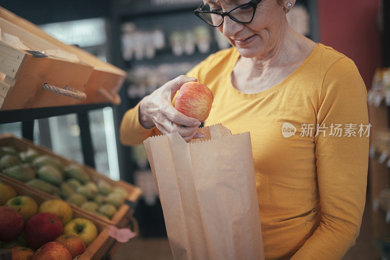 女人用纸袋买水果。