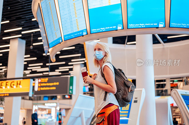 戴着防护口罩、护照和机票的年轻女子在国际机场