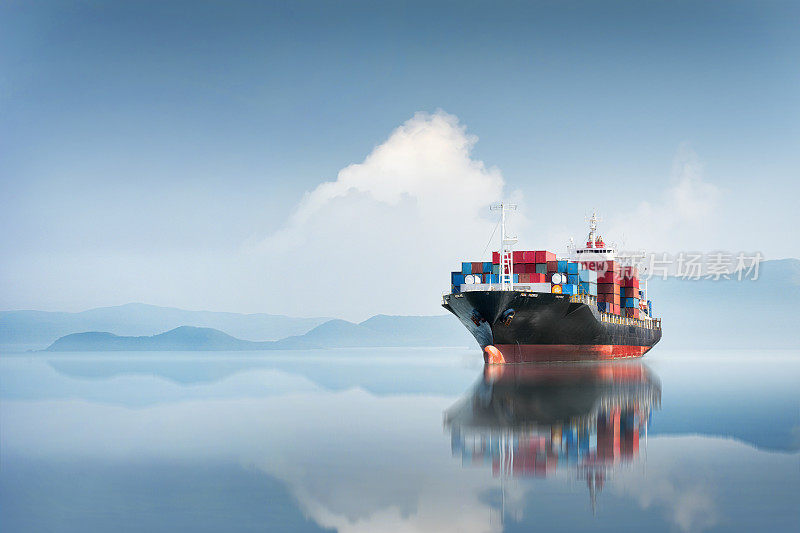 集装箱货轮在海洋日落蓝天的背景下复制空间，全球商务物流进出口货物的货运承运人，运输行业的概念，海上货运航运