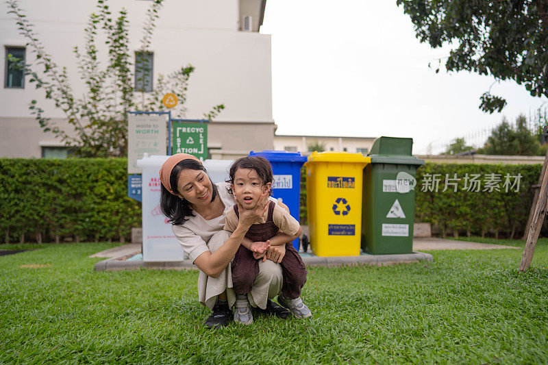 亚洲母亲和儿子把垃圾放在垃圾箱里。