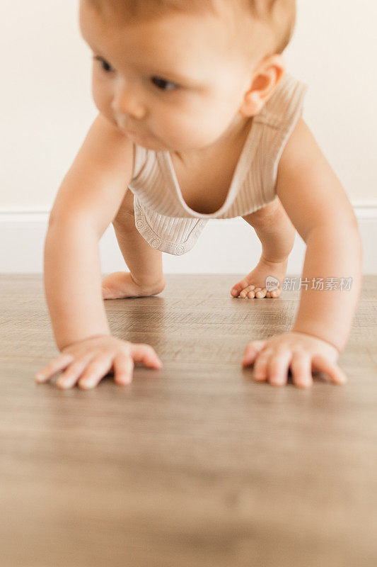 2022年，患有多指畸形的7个月大的男婴穿着橄榄绿颜色的可重复使用和可持续的布尿布，在家里的木地板上以下犬式四肢着地爬行