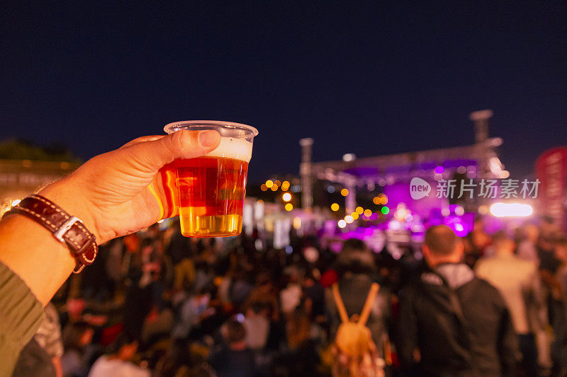 在音乐节上拿着冰镇啤酒塑料杯的人