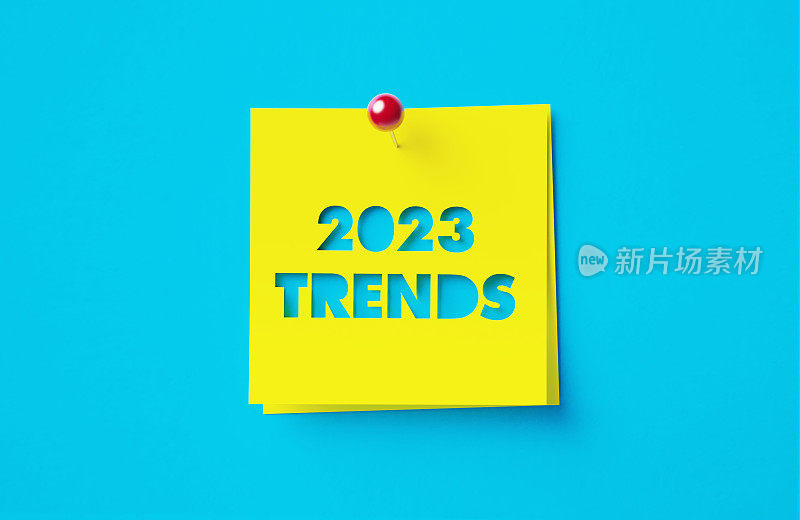 2023年的趋势写的裁剪黄色粘合剂的笔记坐在蓝色的背景