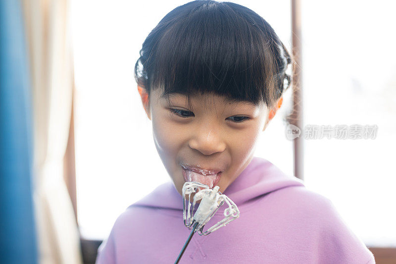 小女孩正在用搅拌器品尝煎饼粉