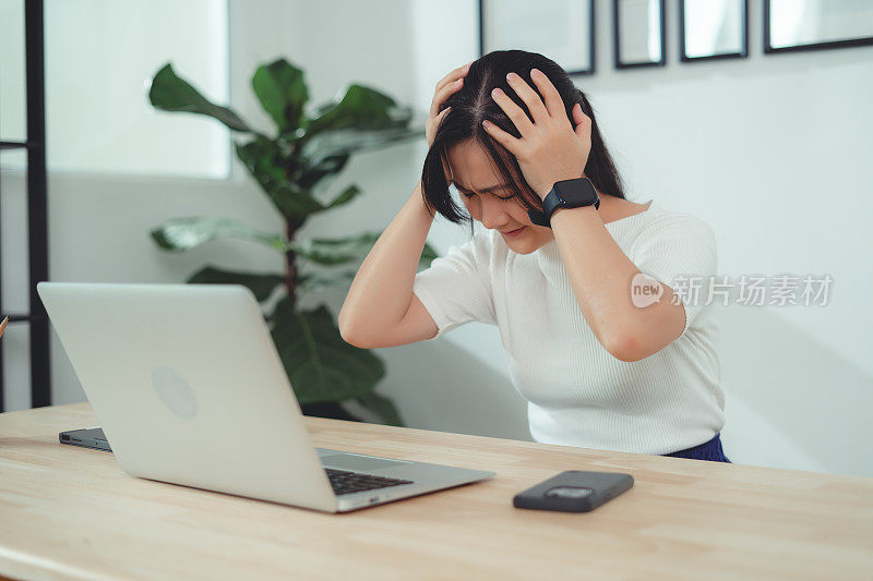 亚洲女性坐在家里头疼。