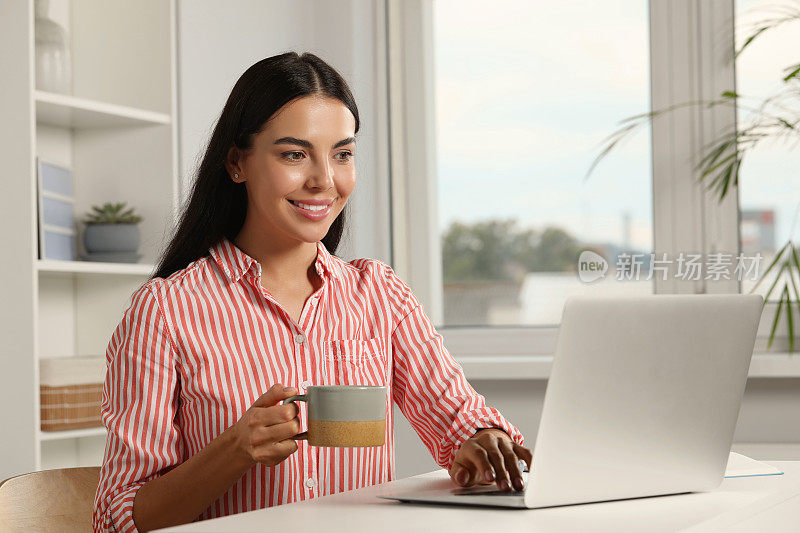 年轻女性在办公室用笔记本电脑工作