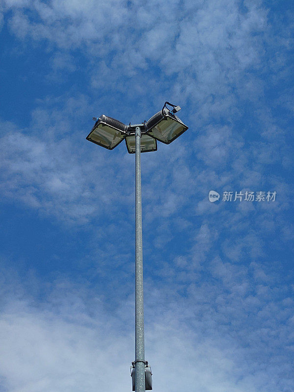 街灯杆映衬着夏日晴朗的蓝天和飘散的白云，近距离拍摄，没有人