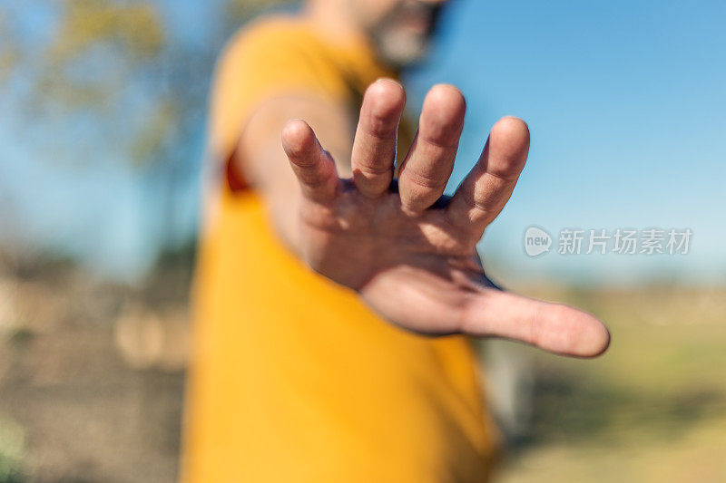 男人的手在户外，伸出或停止的姿态取决于解释。