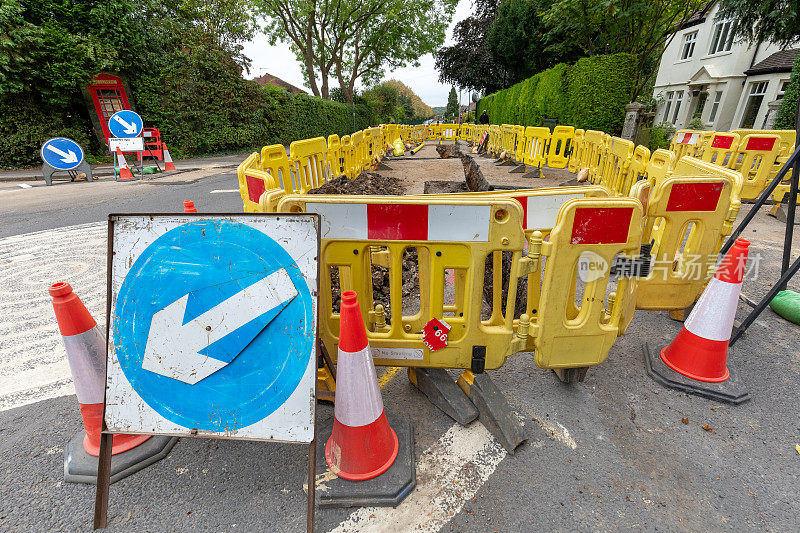 英国的道路工程正在挖掘当地的柏油路面，以修复地下的公用管道，并设置安全屏障和标志