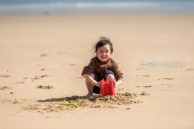 一个中国小女孩在沙滩上玩沙子