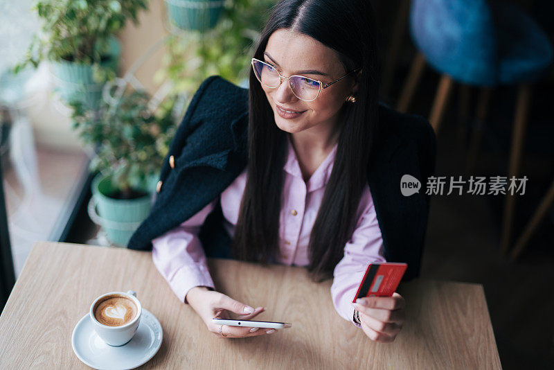 照片中，一位迷人的年轻女子在咖啡馆里使用数码平板电脑上网购物