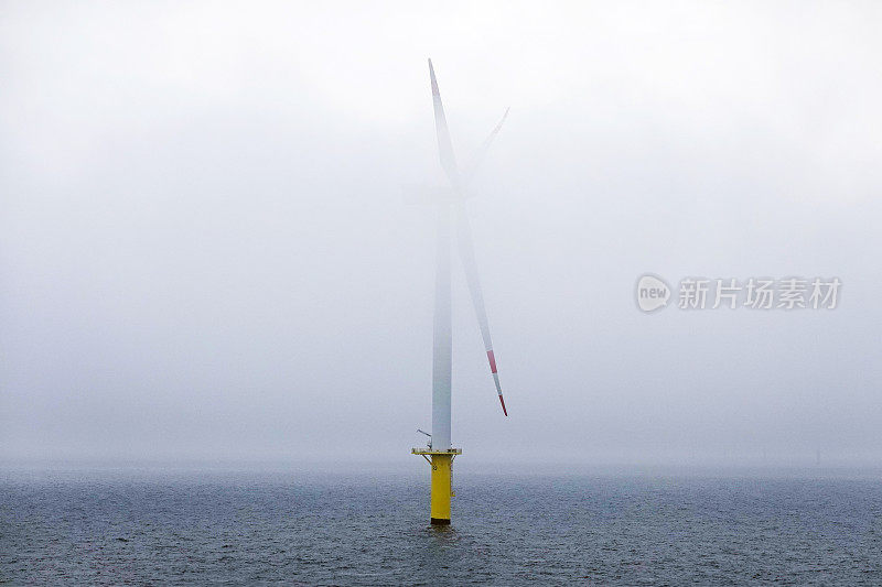 北海的巨型海上风力涡轮机在黎明时分出现在德国博尔库姆附近的云雾中。