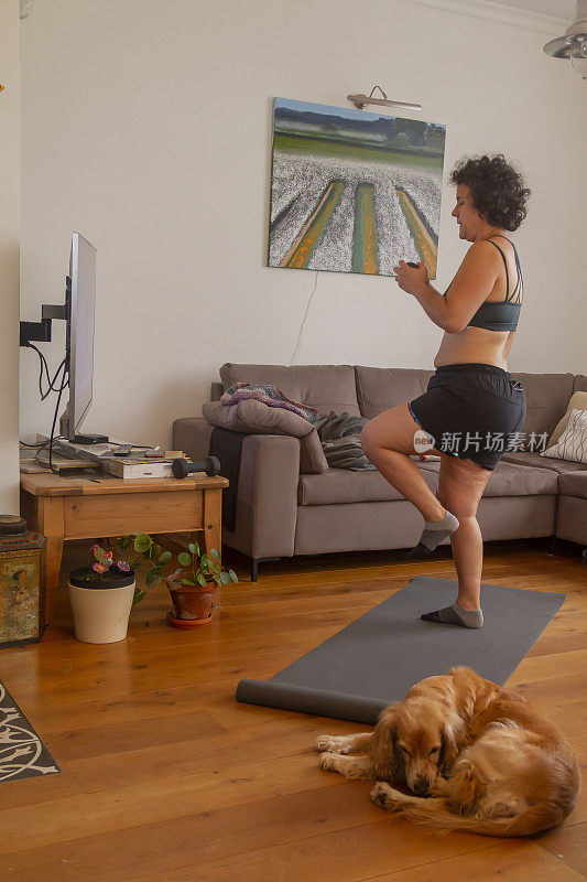 中年成熟妇女做普拉提锻炼的指导下，从私人教练在家里通过电视