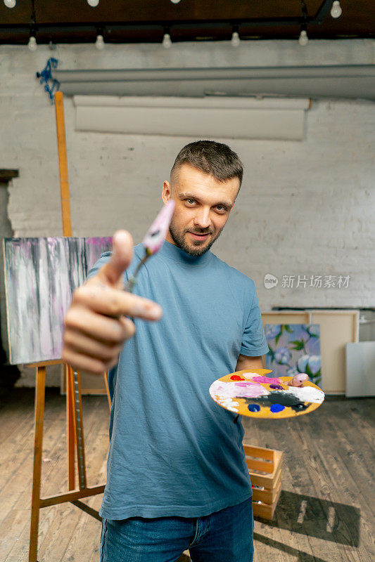 在艺术工作室里，艺术家用调色板刀直接对着相机用眼睛测量