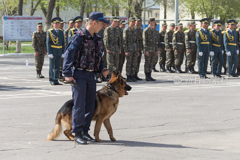 哈萨克斯坦国民警卫队的一名军人和一只德国牧羊犬。一只德国狗在站岗。