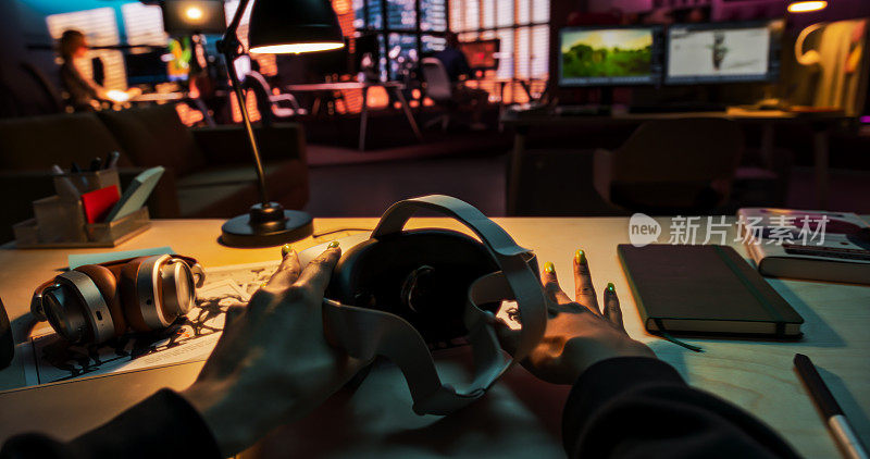 一个人在创意办公室拿起虚拟现实耳机的场景。模拟插入自己的VFX虚拟现实3D宇宙，数字办公界面，社交平台