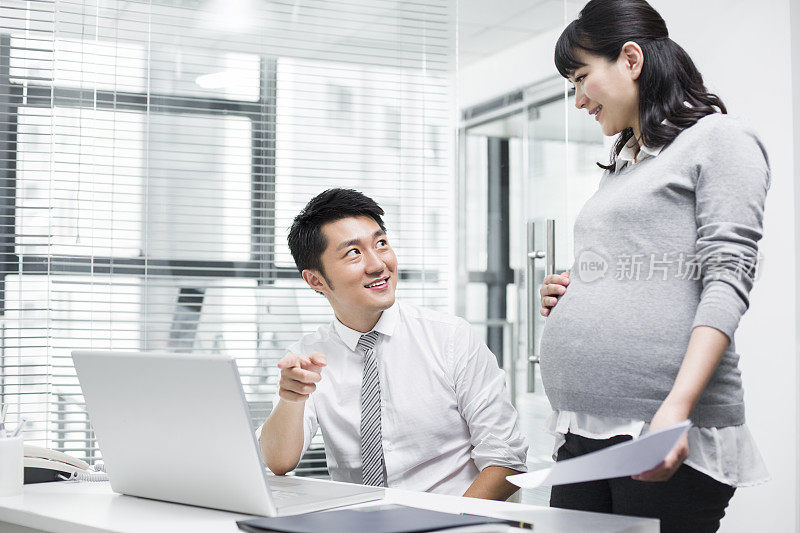 怀孕的商务女士和同事一起工作
