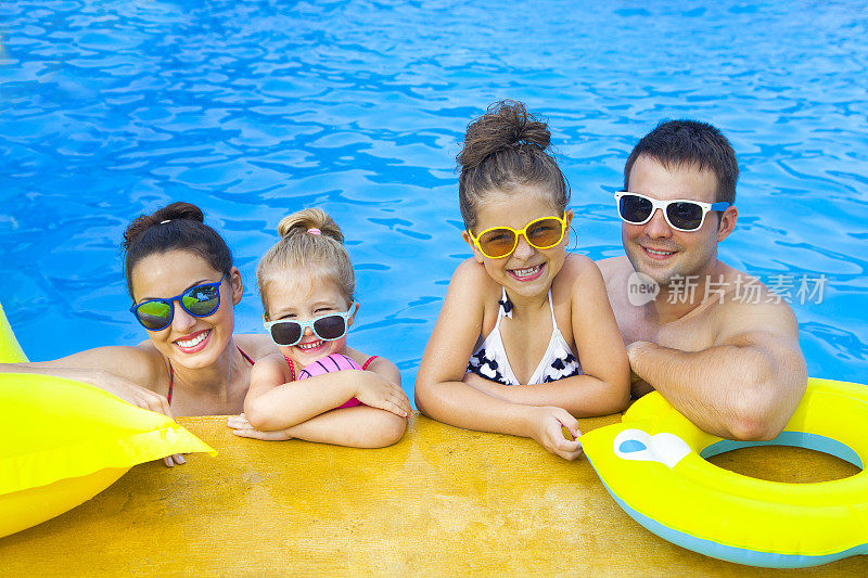 幸福的家庭和两个孩子在游泳池里玩