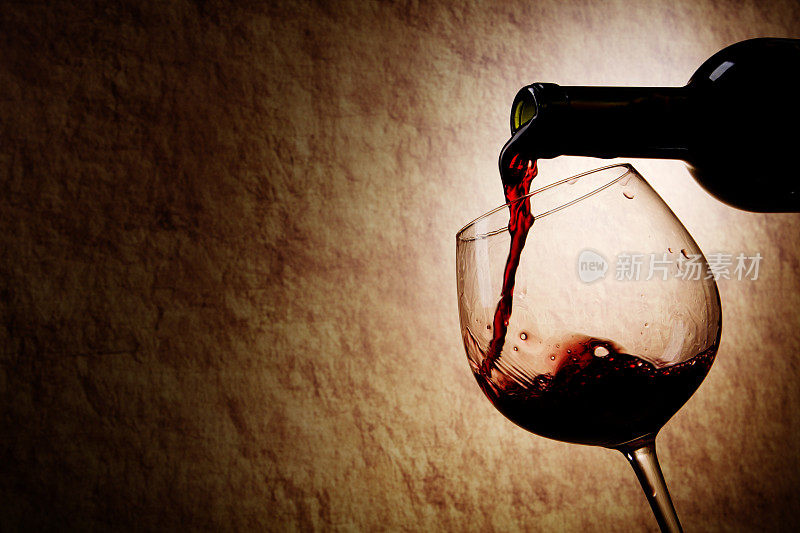 古老的石头背景上的红酒杯和酒瓶