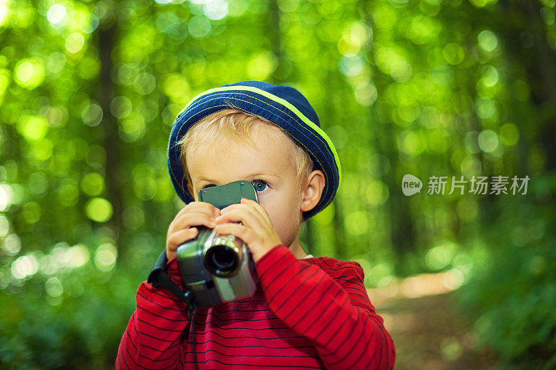 一个孩子带着摄像机在森林里
