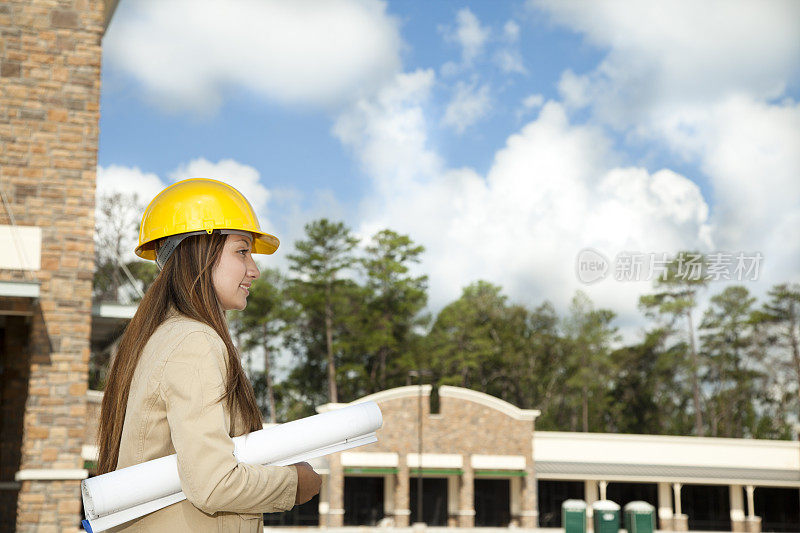 建筑师在商业建筑工地持有平面图。