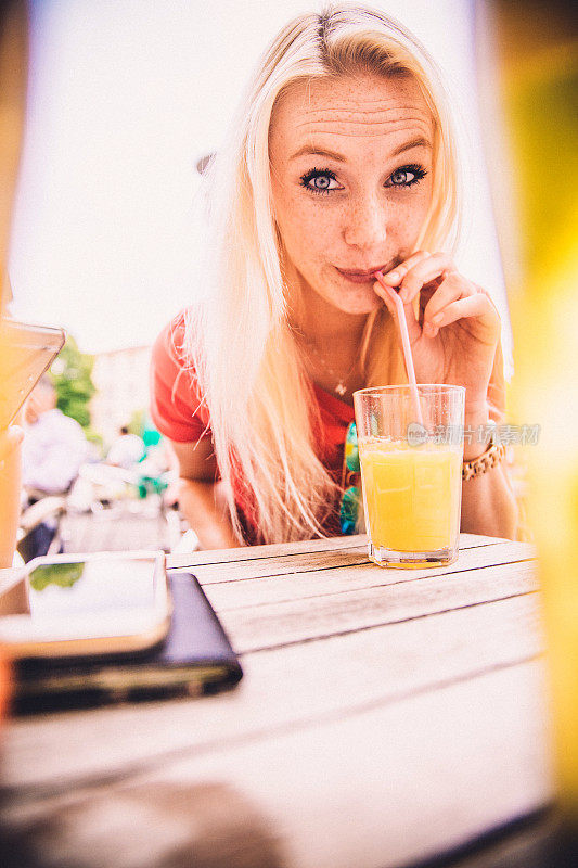 在户外酒吧里喝橙汁的漂亮年轻女人
