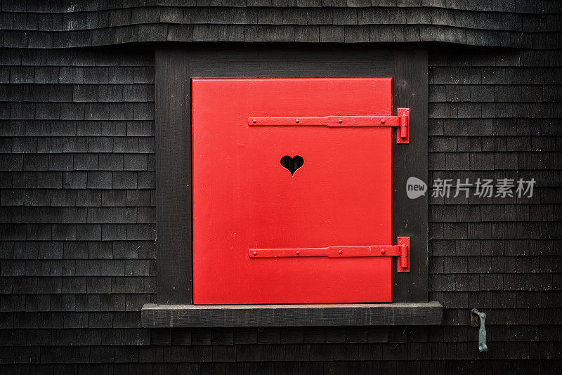 乡村小屋立面上的心形红色折叠百叶窗