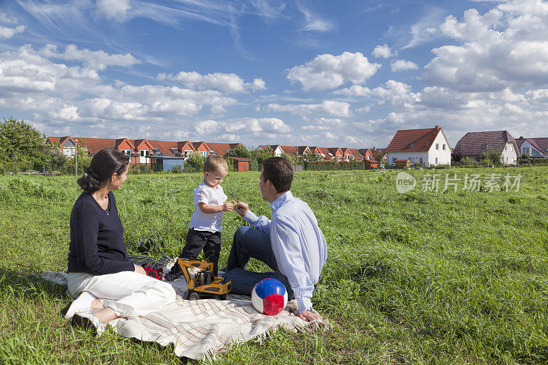 年轻的父母和儿子在户外草地上玩