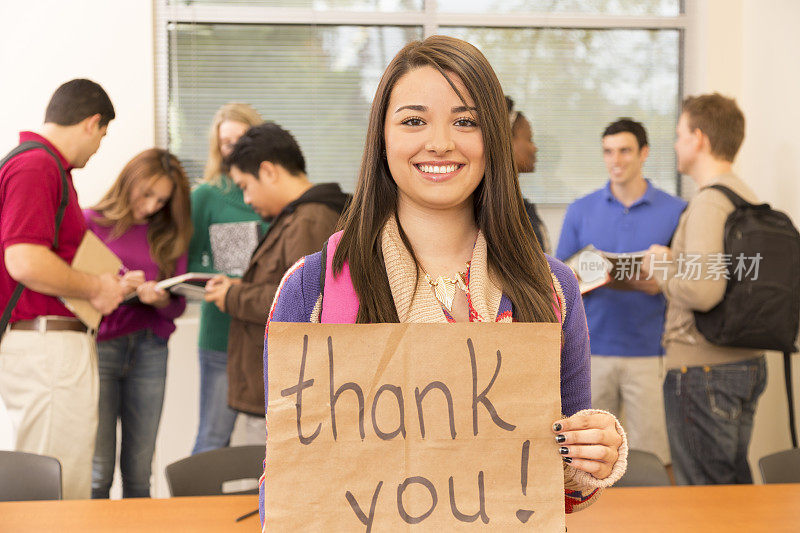 教育背景:拉丁裔大学生举着“谢谢”的牌子。教室。