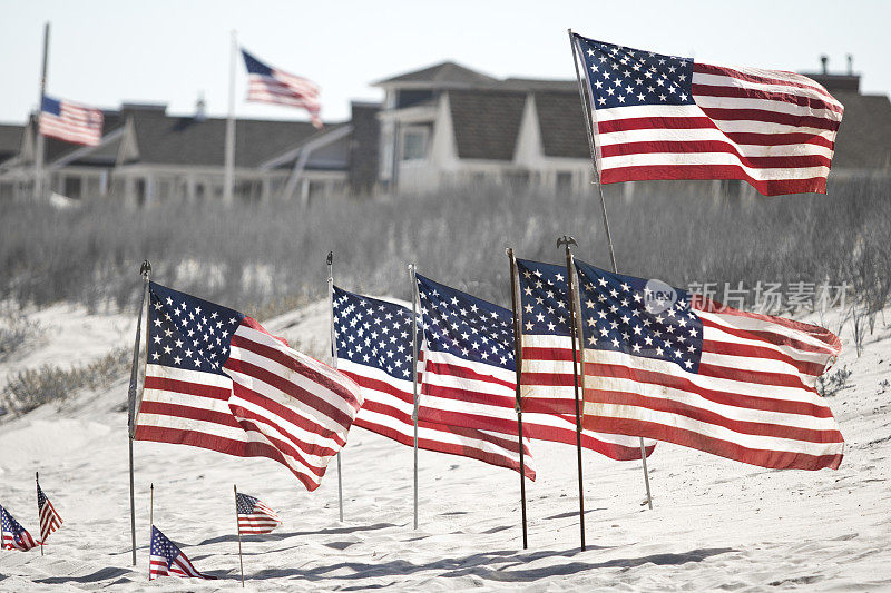 海滩上飘扬着美国国旗，背景是房屋