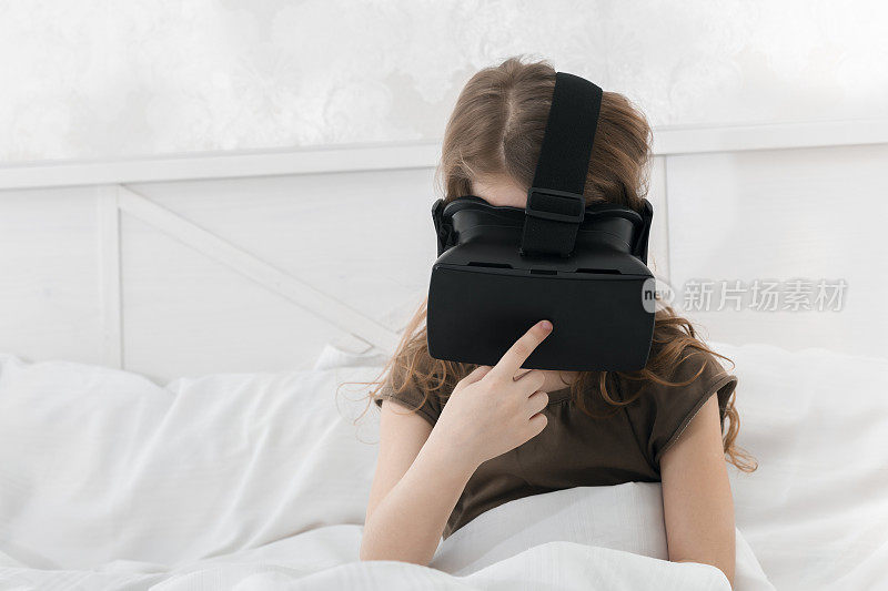 小女孩坐在床上调整VR眼镜