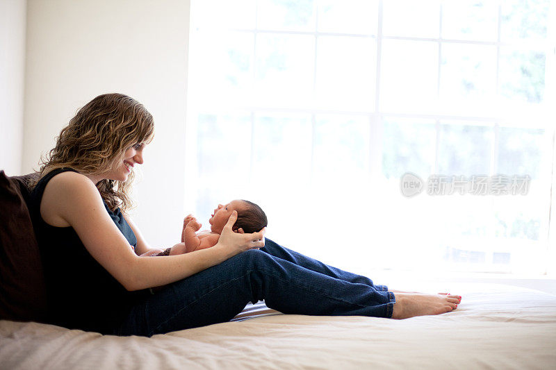 慈爱的年轻母亲抱着新生婴儿的彩色图像