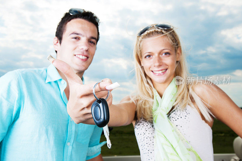 一对漂亮的夫妇展示他们买的车钥匙。
