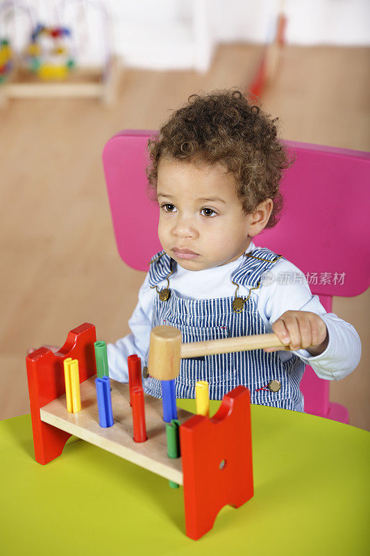 幼儿玩一个多色木制玩具的特写