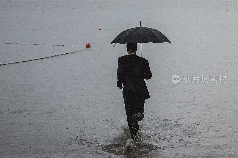 帅气的男人穿着西装，在雨中撑着伞