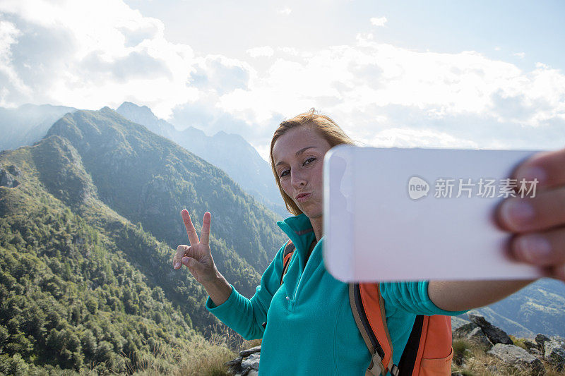 年轻女子徒步旅行用手机自拍