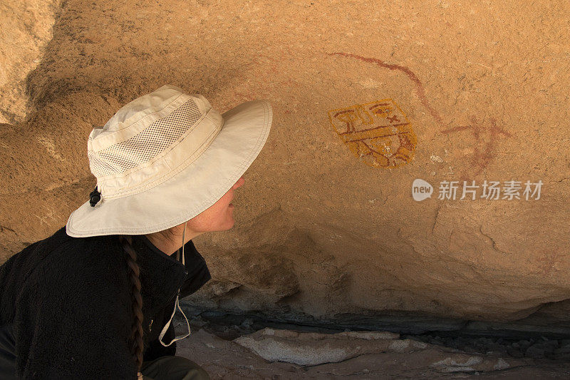 年轻女子钦佩岩石艺术面具Hueco坦克德克萨斯州