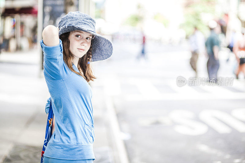 戴着大帽子的少女在街上等着