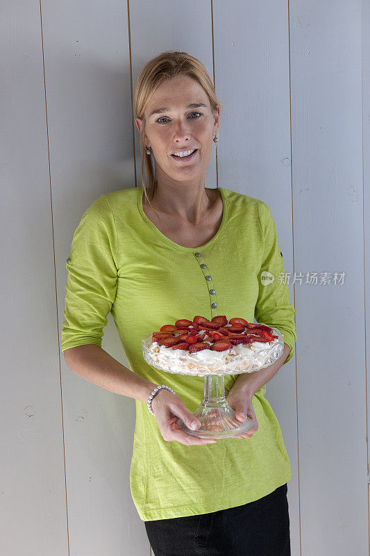 快乐的女人拿着草莓芝士蛋糕