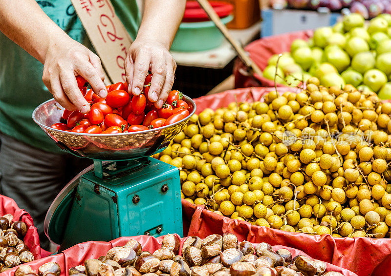 中国香港，一名男子在街边市场称重西红柿