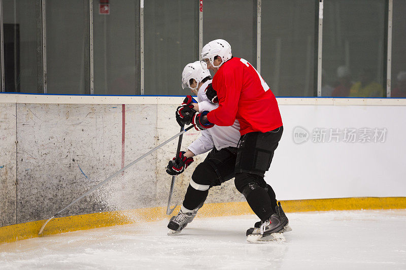 两名冰球运动员在围栏旁决斗