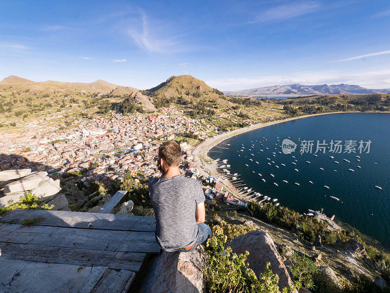 一个年轻人坐在秘鲁的喀喀湖科帕卡巴纳市美丽的风景中