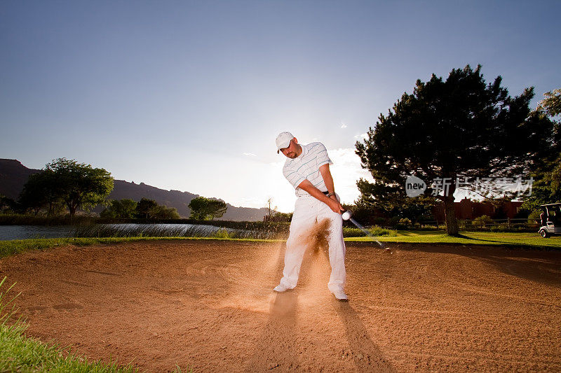 男高尔夫球手使沙坑击球与沙楔