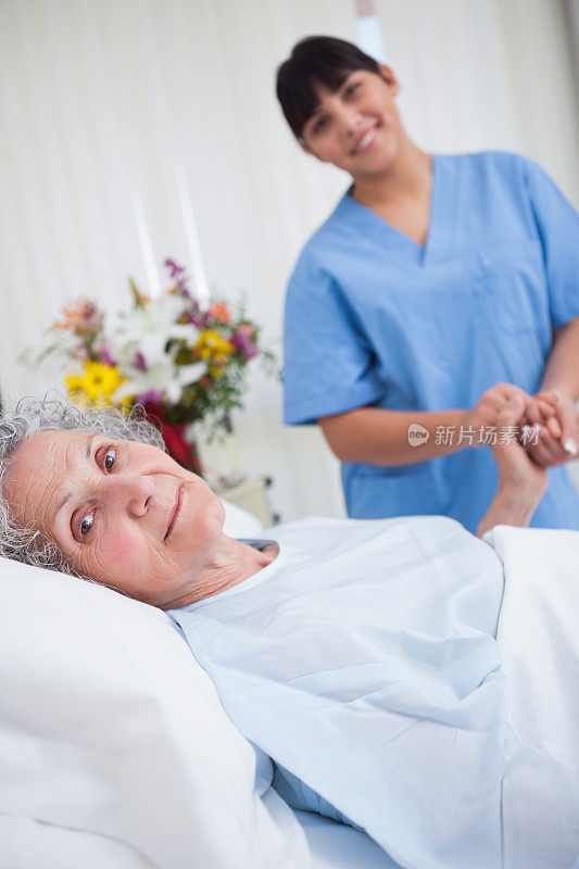 安详的老年病人握着护士的手