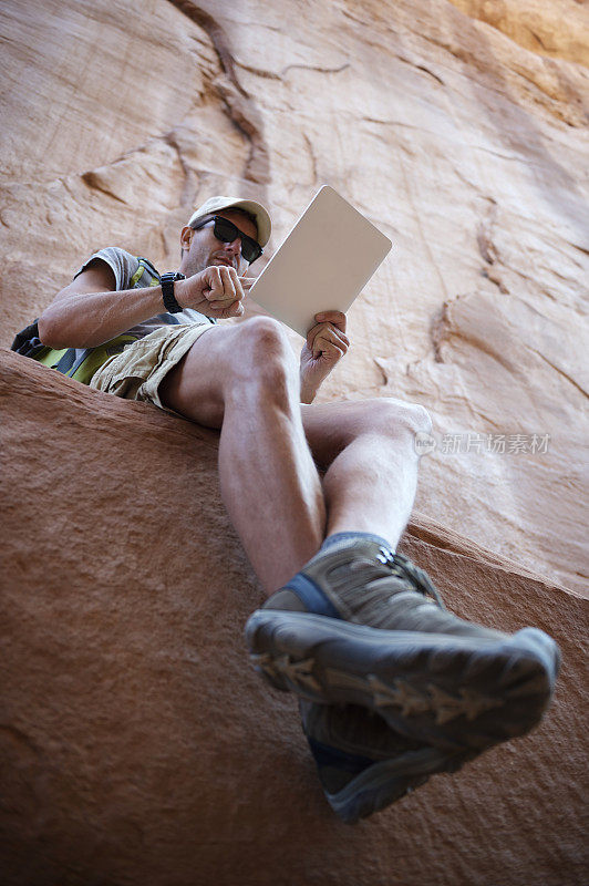 徒步攀岩者使用数码平板电脑休息